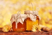 11407255-two-jars-of-honey-and-wooden-drizzler-on-table-on-yellow-background